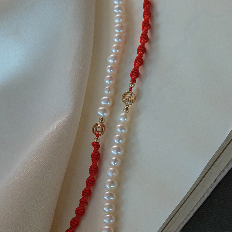 Perlenarmband mit rotem Makramee-Seil und goldfarbenen Verschlüssen elegant drapiert
