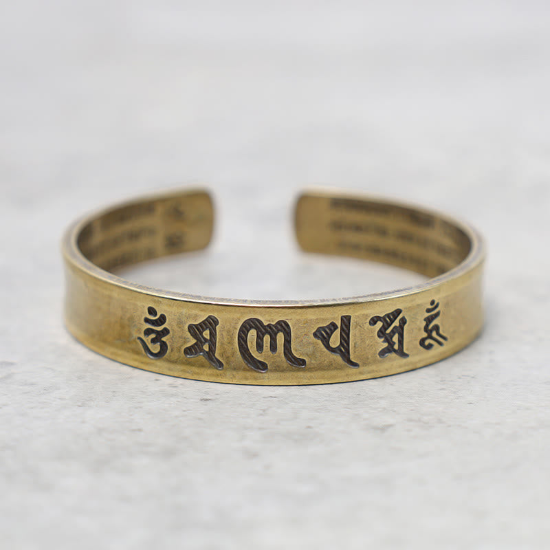 Goldenes Armband Tibet Buddha Mantra Schrift auf Marmor Flatlay