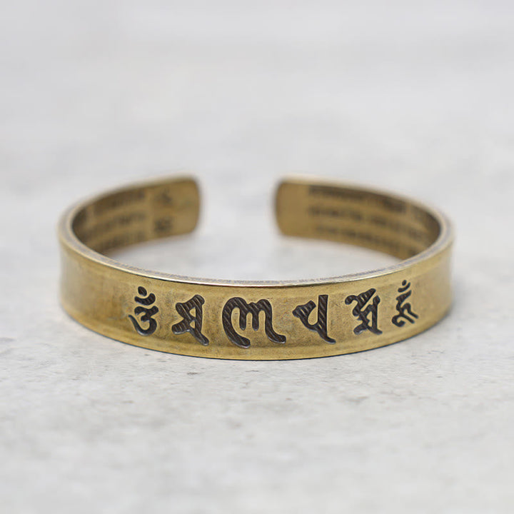 Goldenes Armband Tibet Buddha Mantra Schrift auf Marmor Flatlay