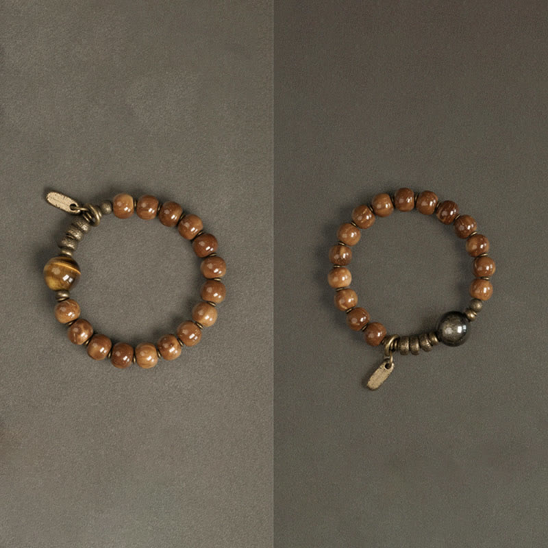 Zwei Tigerauge Armbänder mit Metallperlen auf grauem Hintergrund.