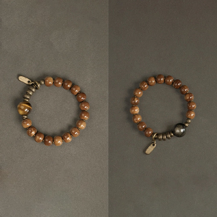 Zwei Tigerauge Armbänder mit Metallperlen auf grauem Hintergrund.