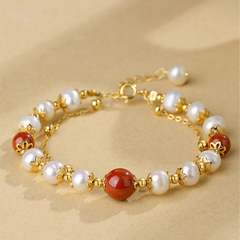 Elegantes Armband mit Perlen und roten Zinnober-Steinen, goldfarben.