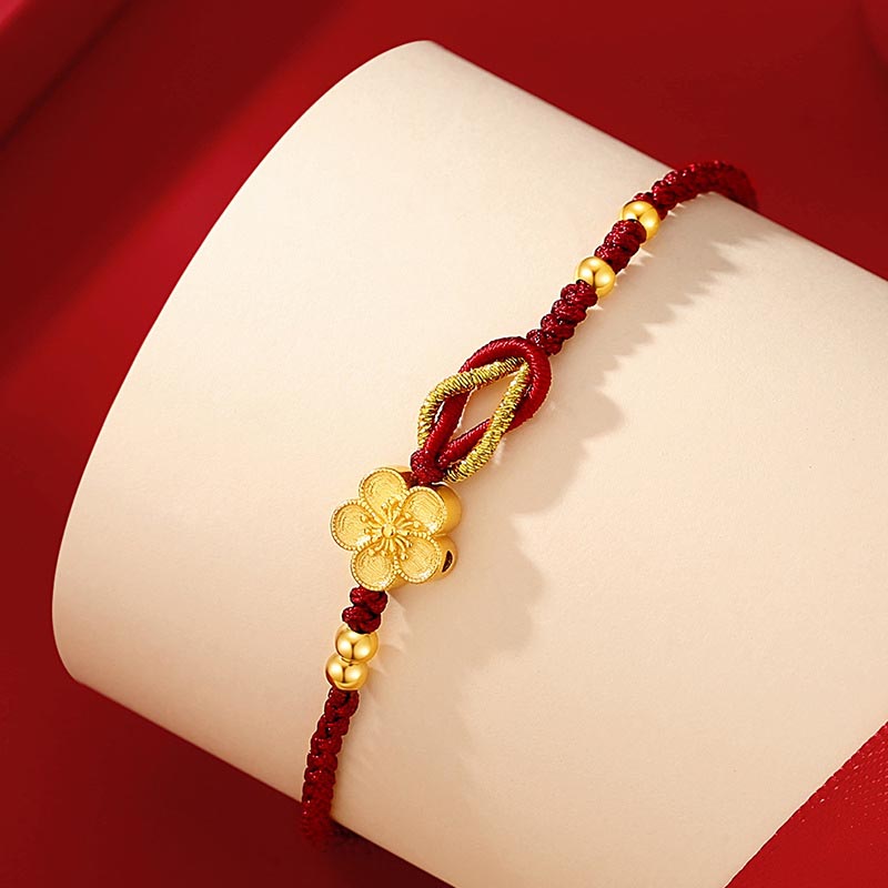 Rotes Armband mit goldenem Blütenanhänger elastisch getragen