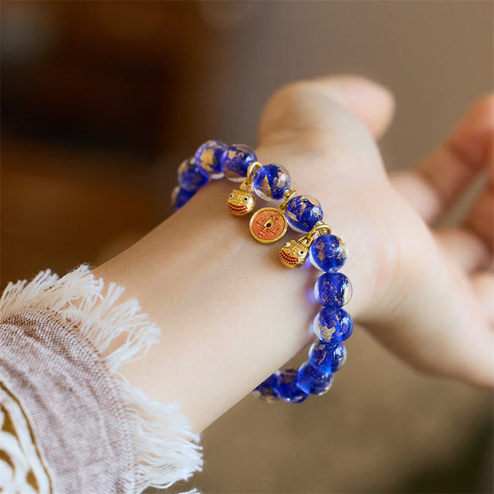 Blaues Lapis Lazuli Armband mit goldenen Glücksmünzen Verschlüssen.