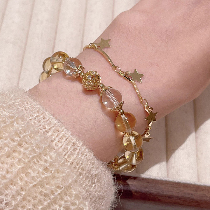 Goldenes Armband mit Citrin Perlen und Stern Anhängern am Handgelenk.