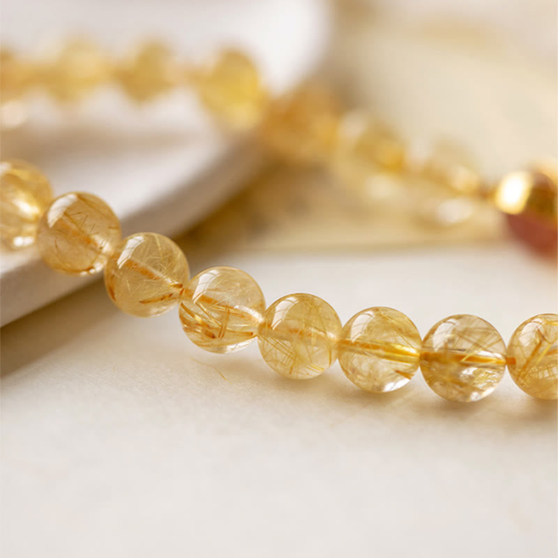 Goldenes Citrin Armband mit durchsichtigen facettierten Perlen auf weißem Hintergrund.