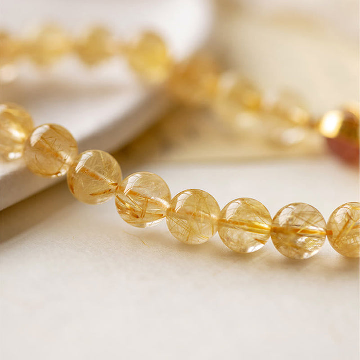 Goldenes Citrin Armband mit durchsichtigen facettierten Perlen auf weißem Hintergrund.