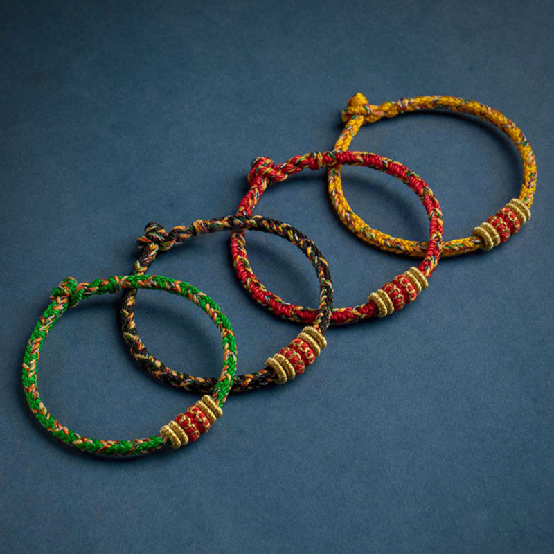 Vier farbige Schutzbuddha Armbänder Glück Stärke auf blauem Hintergrund.
