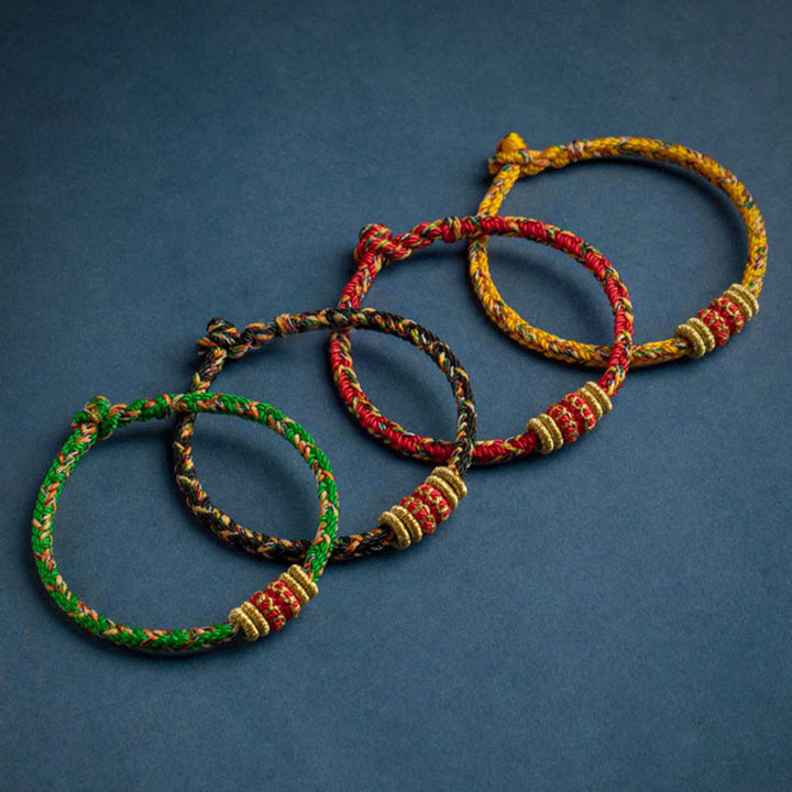 Vier farbige Schutzbuddha Armbänder Glück Stärke auf blauem Hintergrund.