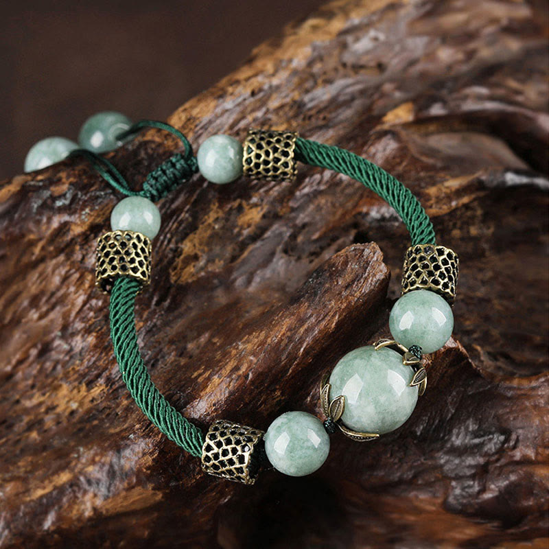 Grünes Jade Armband geflochten mit Glücksperlen auf Holz.