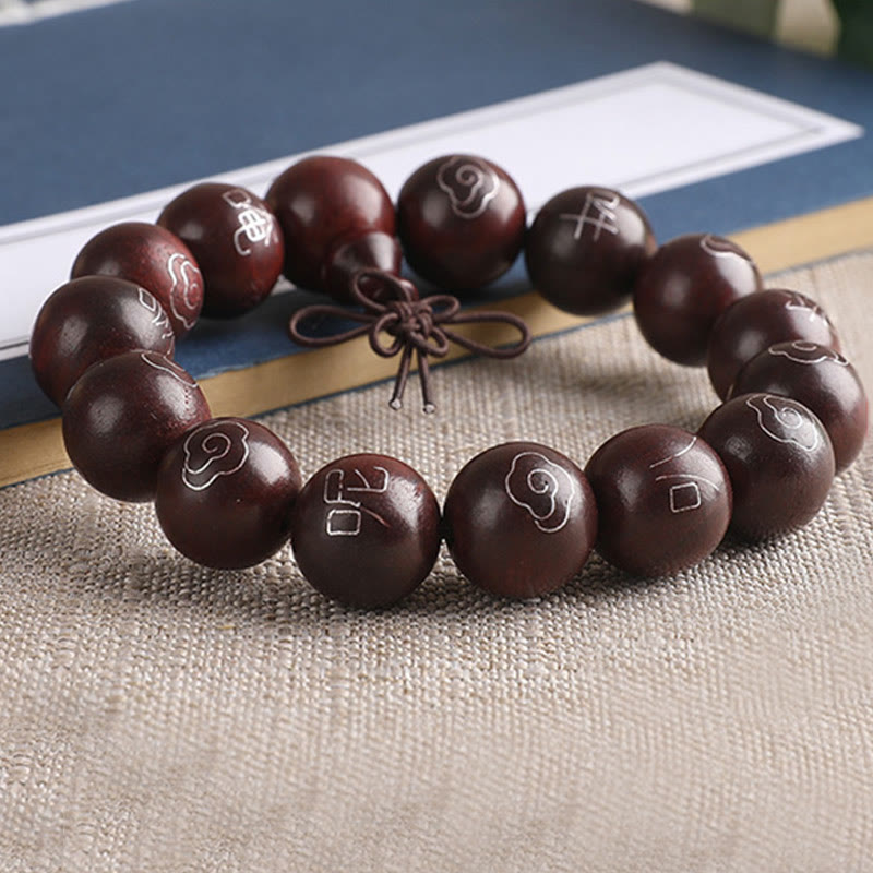 Dunkelbraunes Sandelholz Armband mit Om-Symbolen auf Stoff.