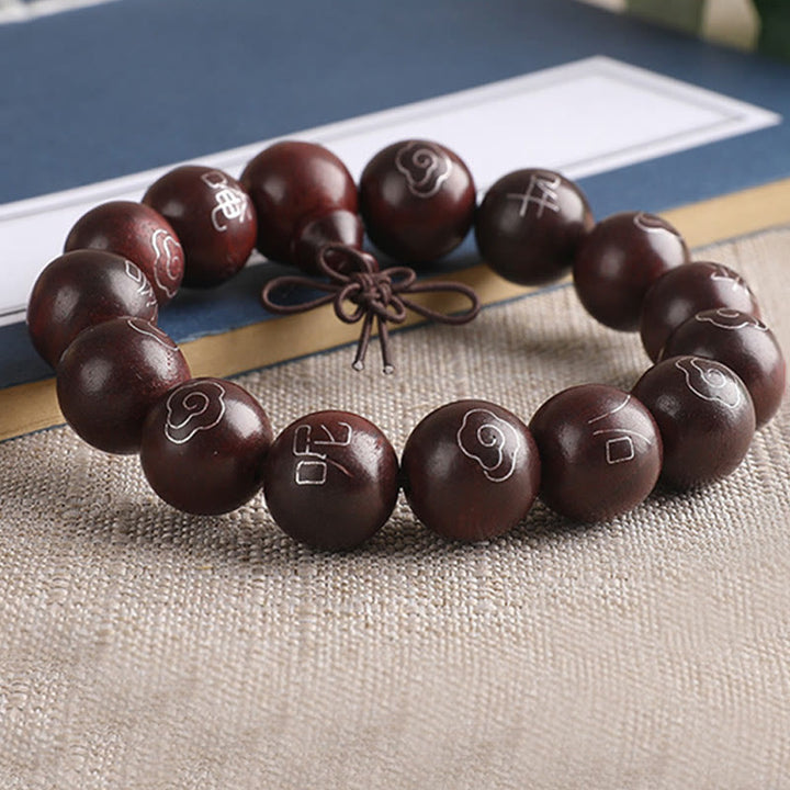 Dunkelbraunes Sandelholz Armband mit Om-Symbolen auf Stoff.