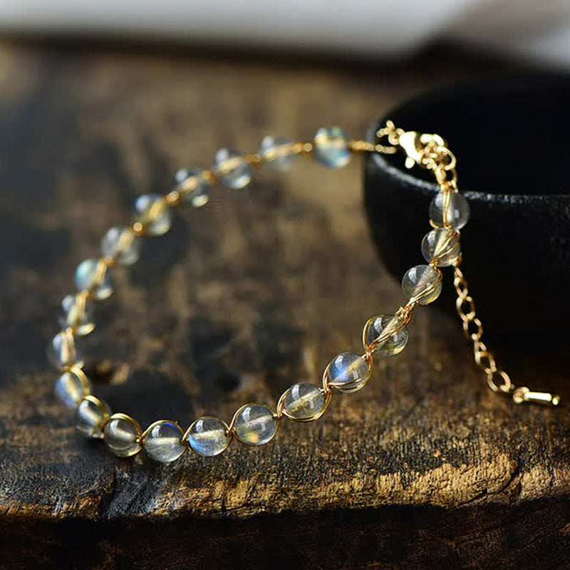 Mondstein Armband Heilung mit goldenem Kettenglied auf Holz Nahaufnahme