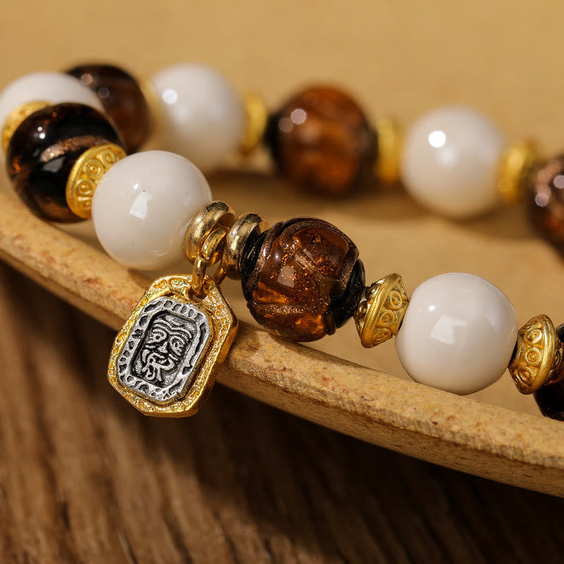 Armband – Schutz & Wohlstand & Balance mit weißen Perlen und braunen Steinen.