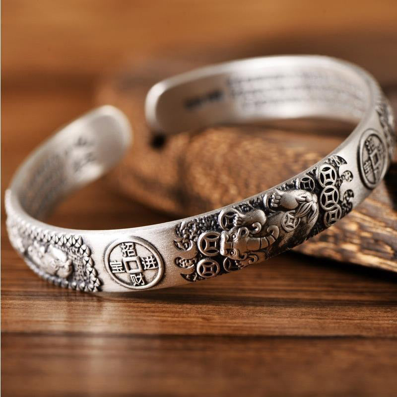 Silberarmband mit Herzsutra und Münzprägung elegant getragen Holzhintergrund