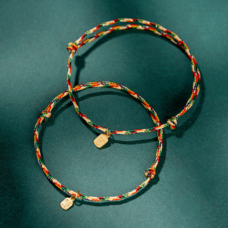 Zwei bunte Armbänder mit Glücksbringern auf grünem Hintergrund elegant arrangiert.