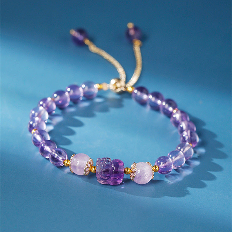 Lila Amethyst Armband mit Erdbeerquarz Perlen auf blauem Hintergrund elegant.