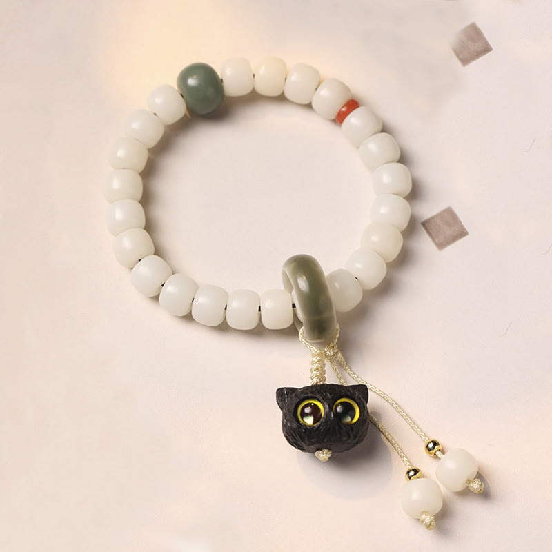 Weißes Bodhi Armband mit grünem Stein und schwarzer Katze Anhänger.