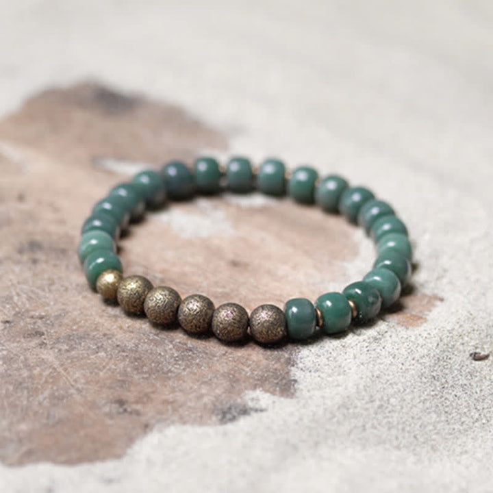 Grünes Bodhi Armband mit Kupperperlen auf Naturstein Hintergrund.