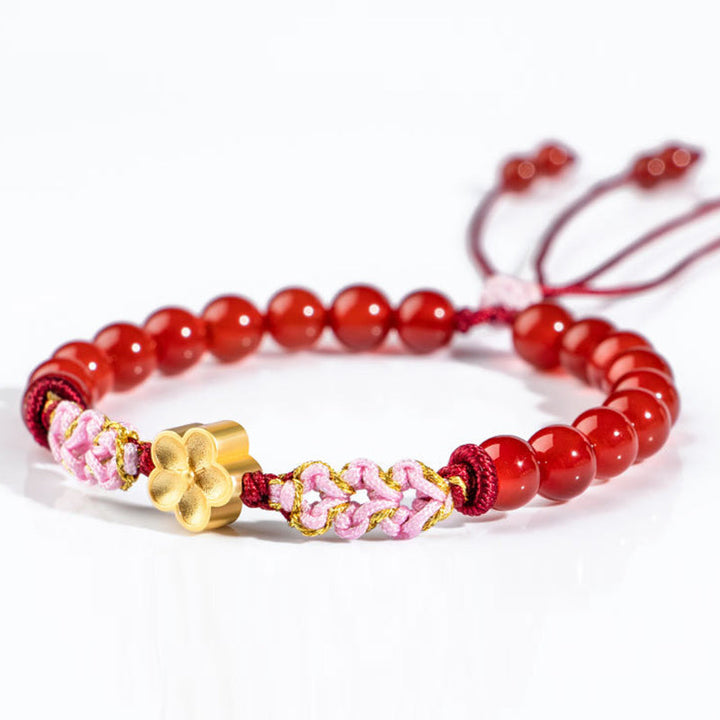 Rotes Achat Armband mit goldenem Blütenanhänger elastisch getragen.