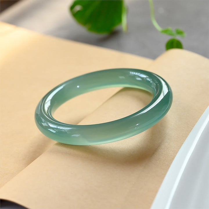 Grünes Chalcedon Armband Armreif auf beiger Oberfläche eleganter Naturstein