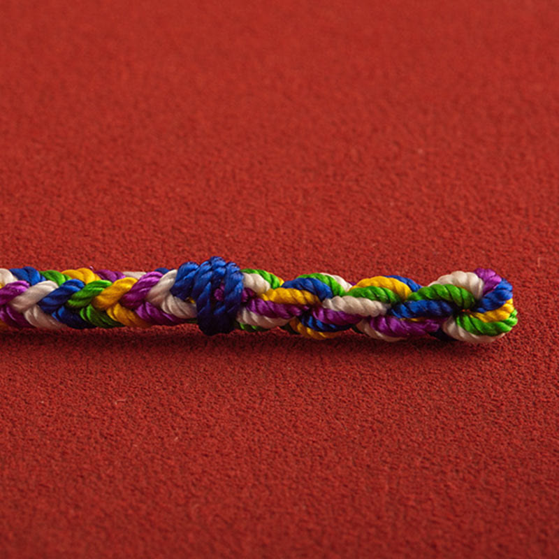 Buntes geflochtenes Armband auf rotem Hintergrund Glück Stein.