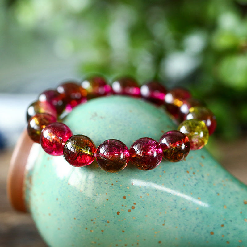 Tourmaline Armband mit roten und braunen Perlen auf türkisem Keramiktopf Nahaufnahme