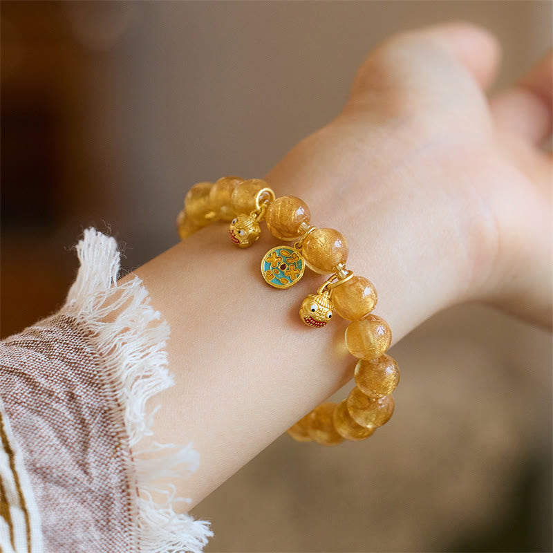Goldenes Armband mit Perlen und Anhängern am Handgelenk getragen.