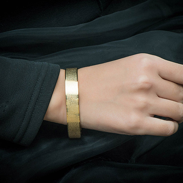 Goldenes Armband mit weißem Stein am Handgelenk getragen elegant