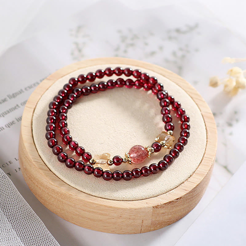 Rotes Granat Armband mit Erdbeerquarz auf Holzständer präsentiert.