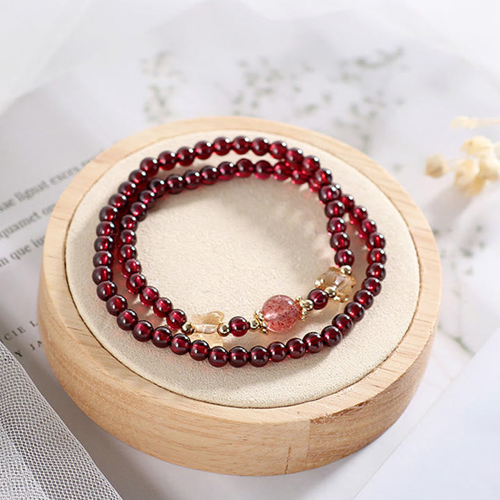 Rotes Granat Armband mit Erdbeerquarz auf Holzständer präsentiert.