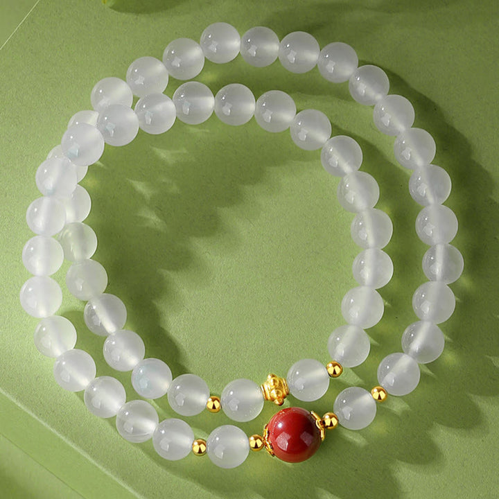 Weißes Jade Armband mit rotem Zinnober Stein elegant präsentiert.