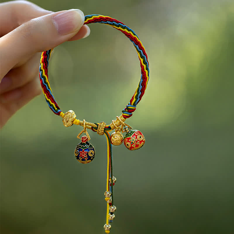 Buntes Seidenarmband mit goldenen Glückscharms und Perlen.