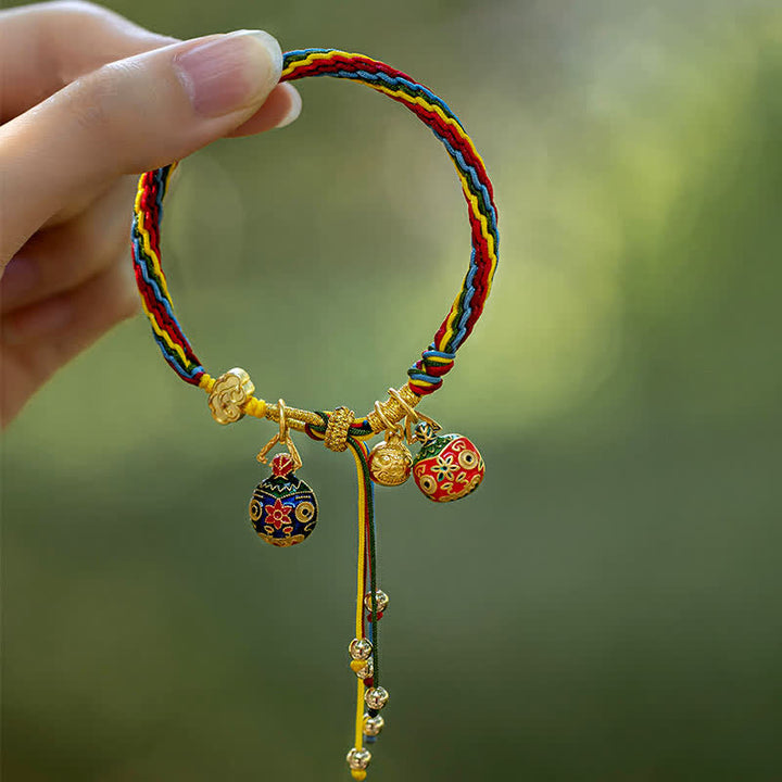 Buntes Seidenarmband mit goldenen Glückscharms und Perlen.