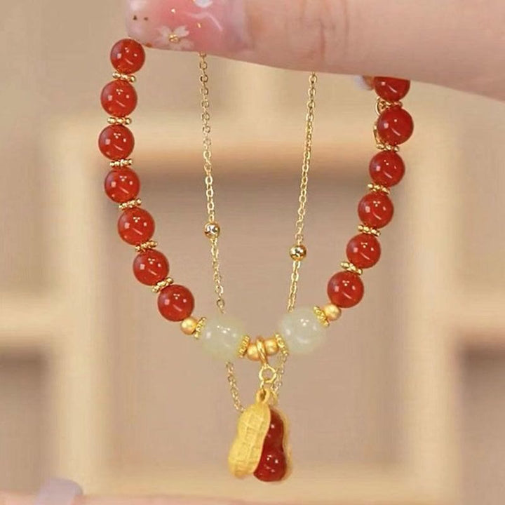 Rotes Jade Armband mit goldenen Perlen und Anhänger elegant getragen.