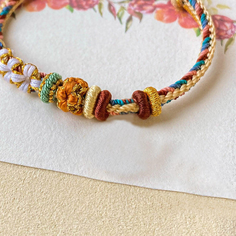 Armband Pfirsichblüte mit goldenen Perlen und bunten Fäden elegant.