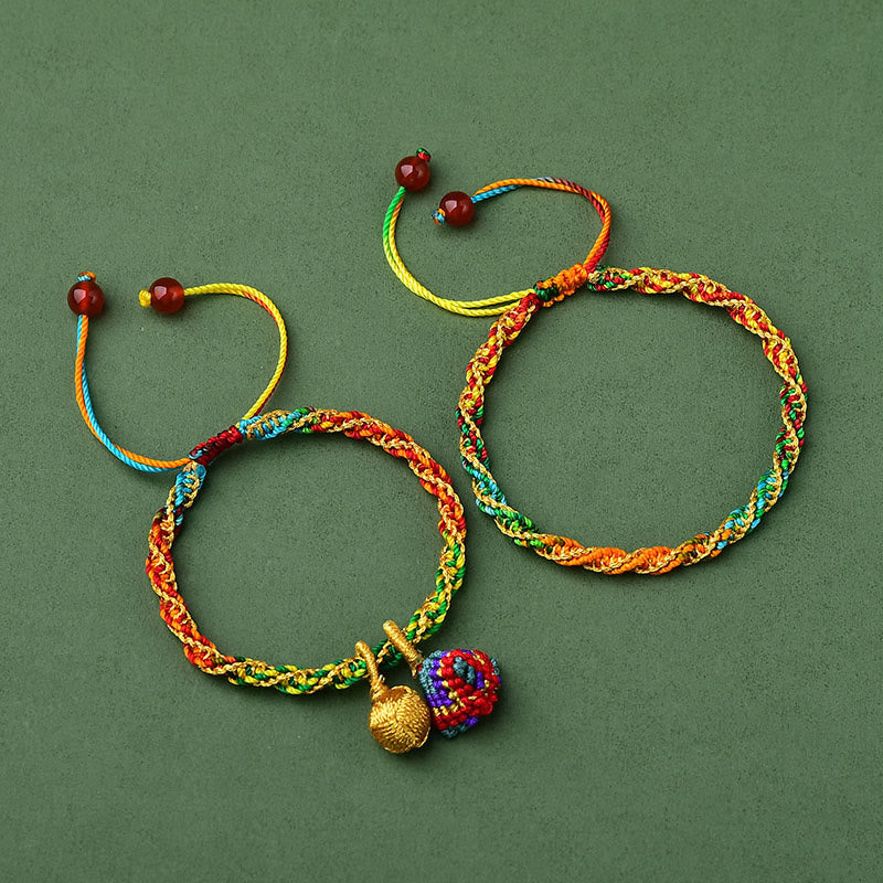 Bunte Armbänder mit roten Perlen und Glückszongzi Anhängern auf grünem Hintergrund.