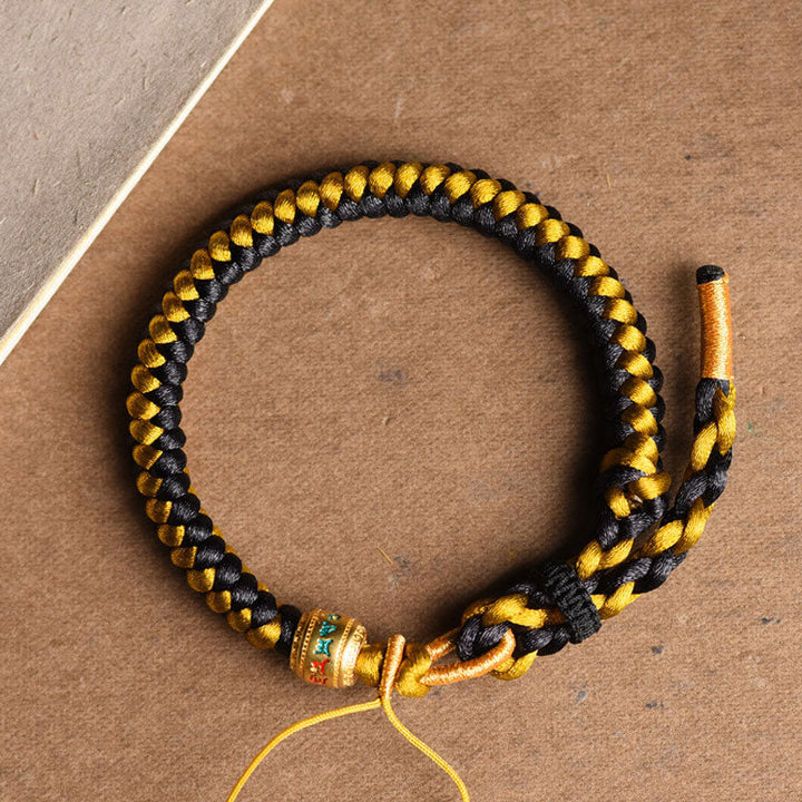 Geflochtenes Armband Om Mani Padme Hum Gold Schwarz Handgelenk getragen.