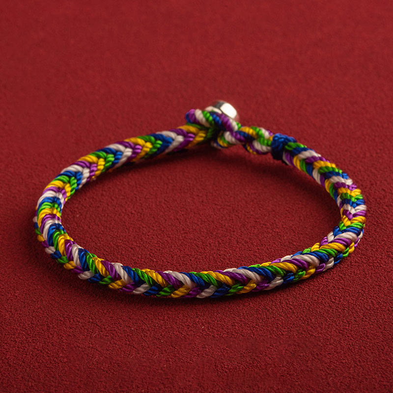 Buntes geflochtenes Armband mit Glück Symbol auf rotem Hintergrund.
