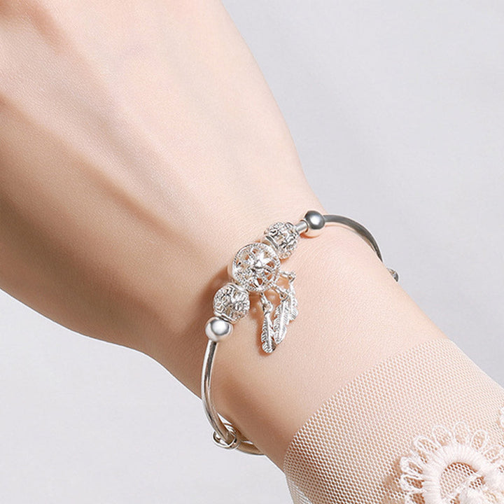 Silbernes Armband mit Flügel-Charm am Handgelenk getragen elegant