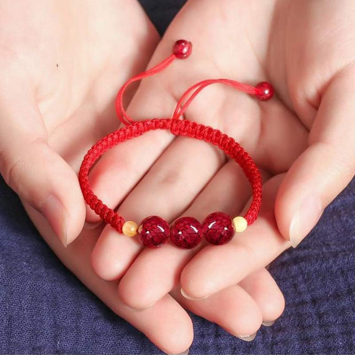 Rotes Armband Zinnober – Segen mit Perlen in Händen gehalten Nahaufnahme