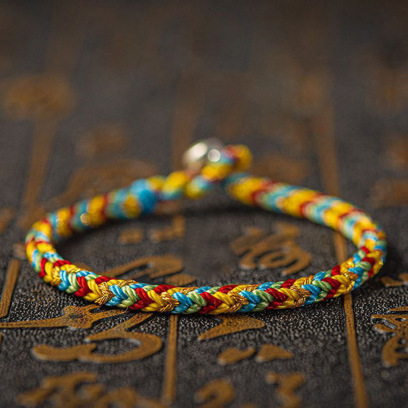 Buntes Armband – Glück & Erfolg auf dekorativem Hintergrund, Flachaufnahme, geflochten.