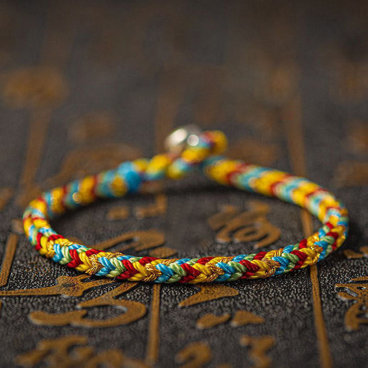 Buntes Armband – Glück & Erfolg auf dekorativem Hintergrund, Flachaufnahme, geflochten.