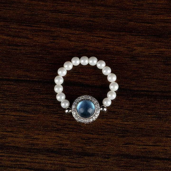 Elegantes Perlenarmband mit blauem Stein silberner Fassung Holzhintergrund
