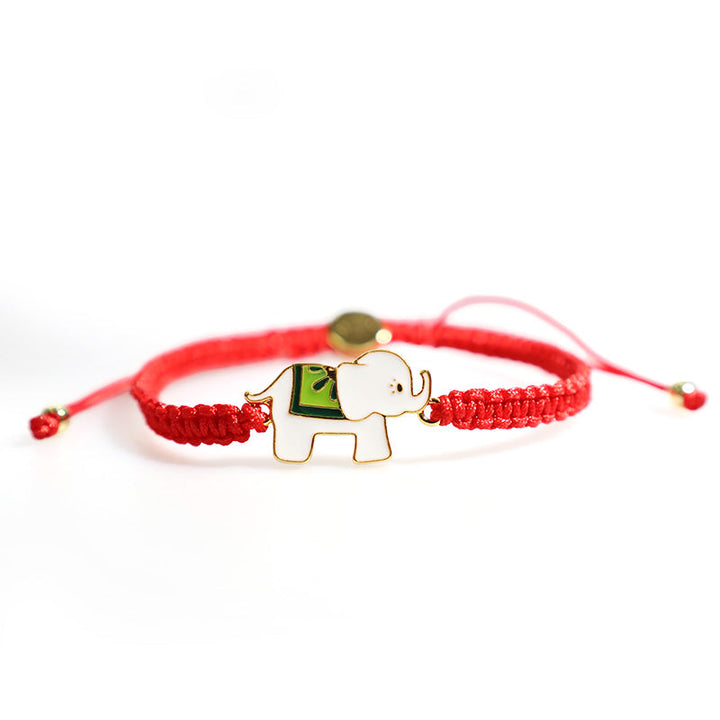 Rotes Armband mit goldenem Elefant Charm am Handgelenk getragen.