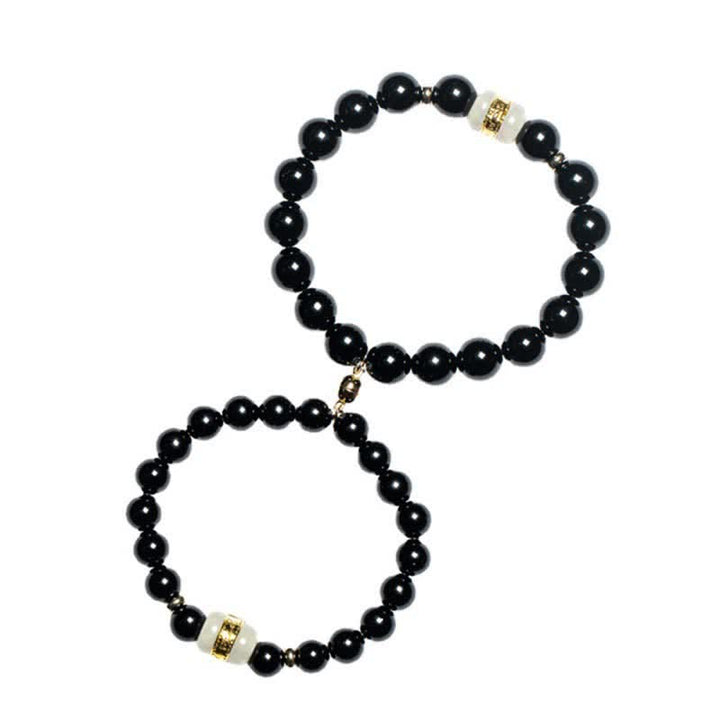 Zwei schwarze Obsidian Armbänder mit goldenen Perlenspacern elegant angeordnet.