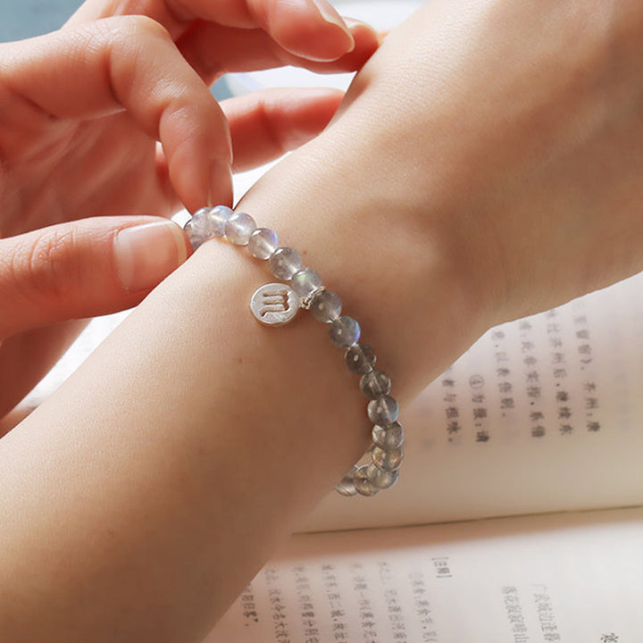 Mondstein Armband mit Charm am Handgelenk getragen, transparent glänzend