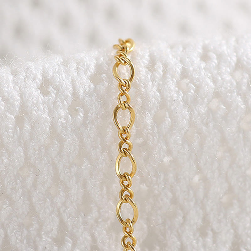 Goldenes Kettenarmband auf weißem Strickstoff getragen elegant.