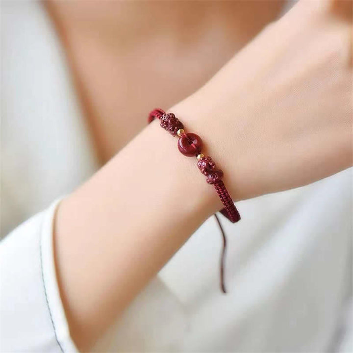 Zinnober Kupfer Pixiu Armband am Handgelenk, rotes elastisches Armband getragen.