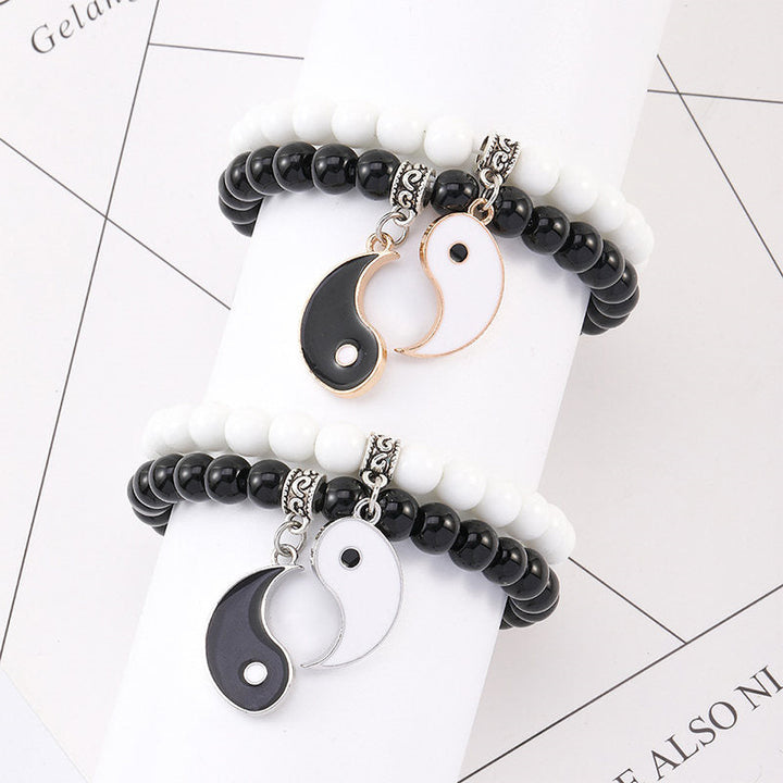 Zwei Yin-Yang Armbänder mit schwarzem Onyx und weißen Perlen flach präsentiert.